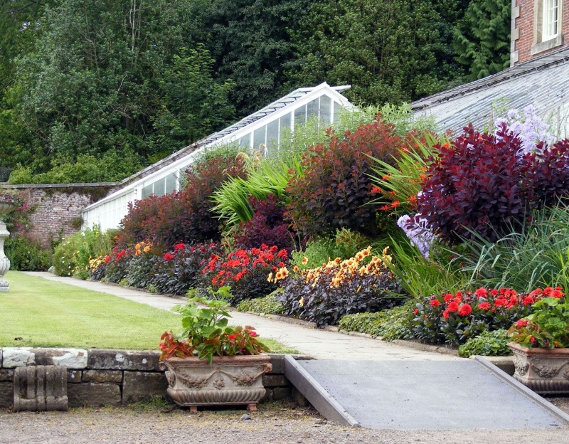Mixborder de fleurs et d'arbustes sur la pente d'un chalet d'été