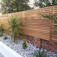 Clôture en bois faite de lattes horizontales sur un socle en brique