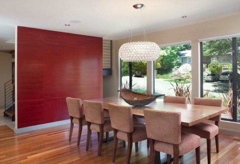 Una buena combinación de una pared roja con sillas de color beige oscuro en el comedor.