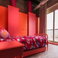 Dormitorio rojo con cama de metal.