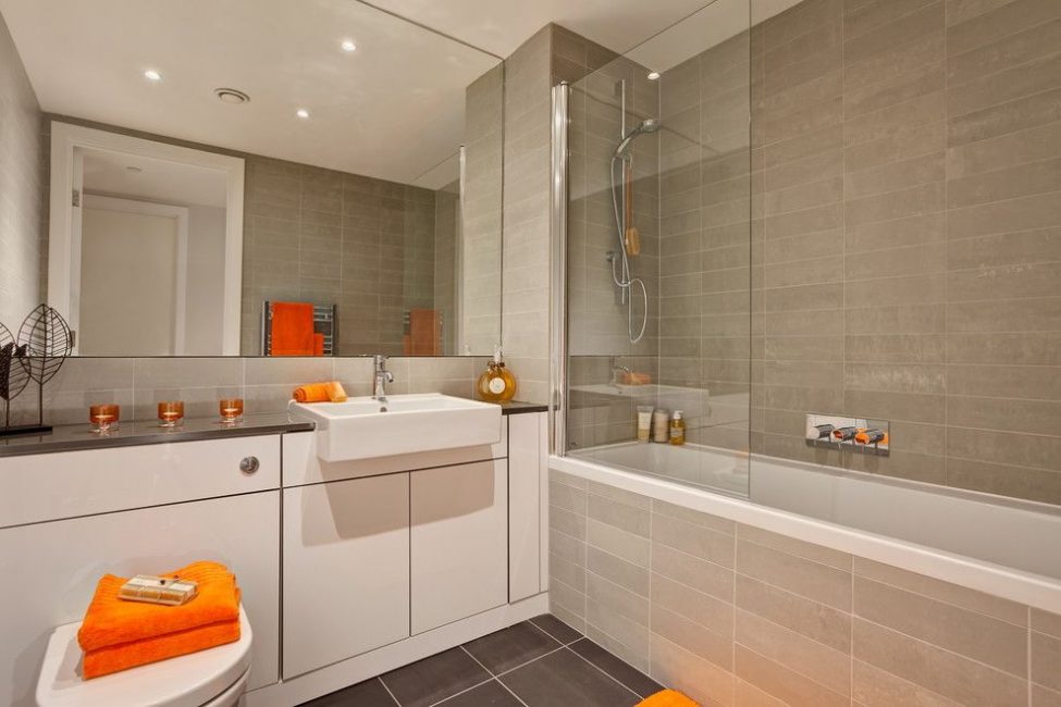 Toalla naranja en el baño con un espejo grande