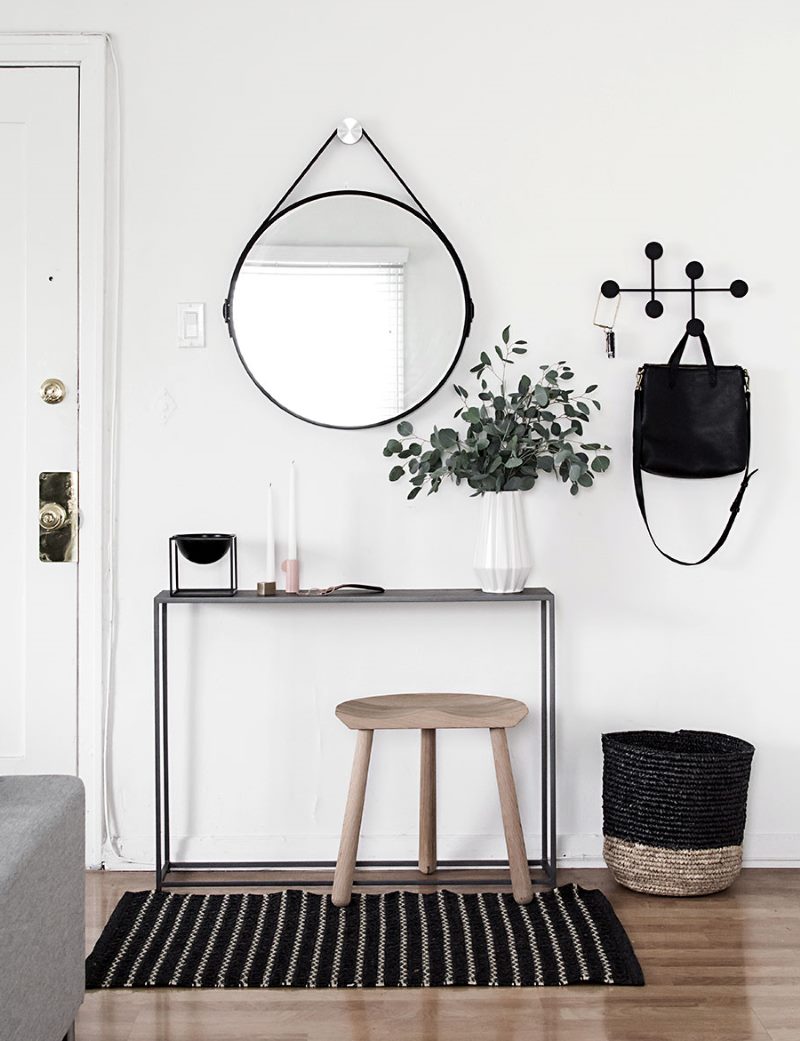 Miroir rond dans un cadre noir sur le mur blanc du couloir