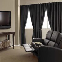 Rideaux noirs dans la chambre avec fauteuil de massage.