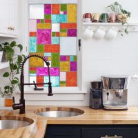 Une petite fenêtre avec des vitraux au dessus de l'évier de la cuisine