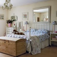Coffre en bois devant un lit avec un cadre forgé