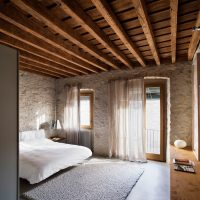 Techo de madera en el dormitorio con paredes de piedra.
