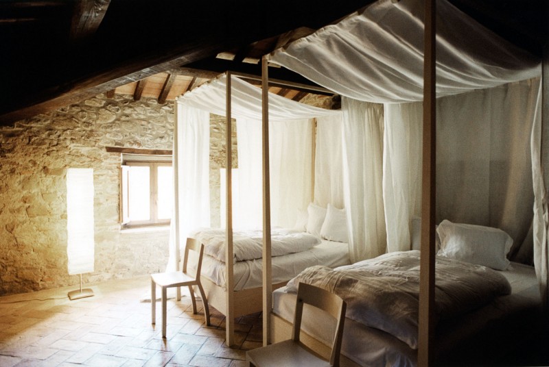 Camas simples con dosel en una habitación con paredes de piedra