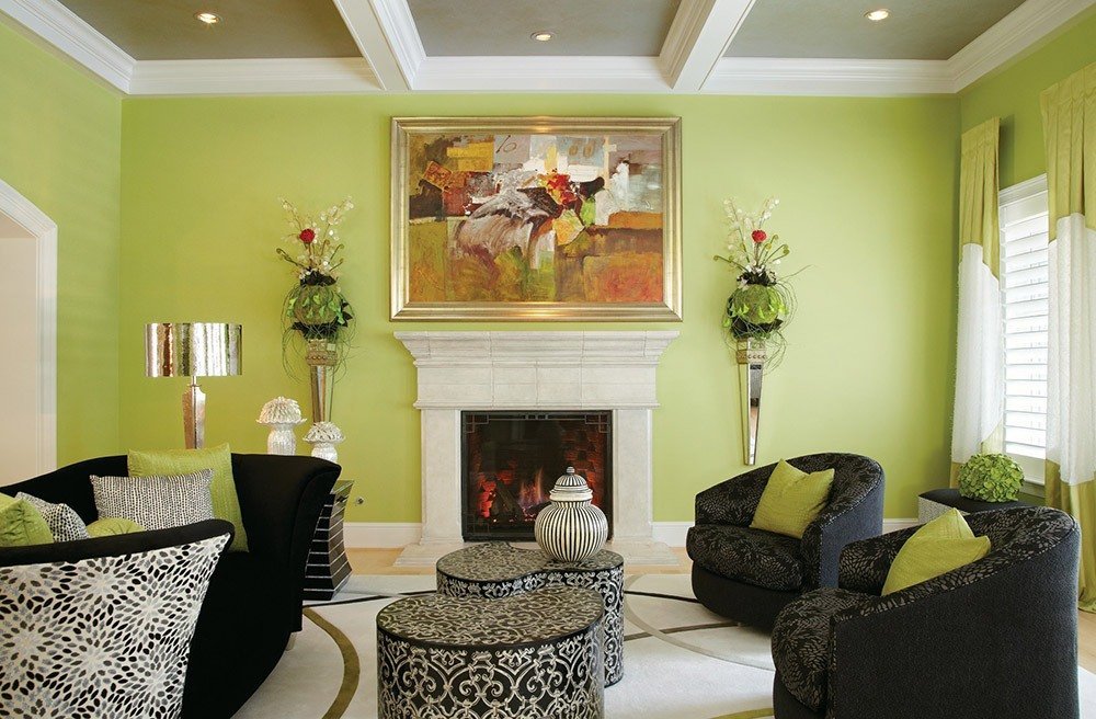 Muebles de sala negros con paredes de color verde claro.